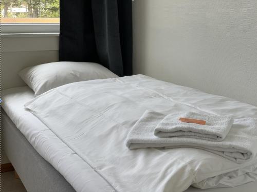 BORG Sommerhotell في Spjelkavik: سرير عليه مناشف بيضاء مع نافذة