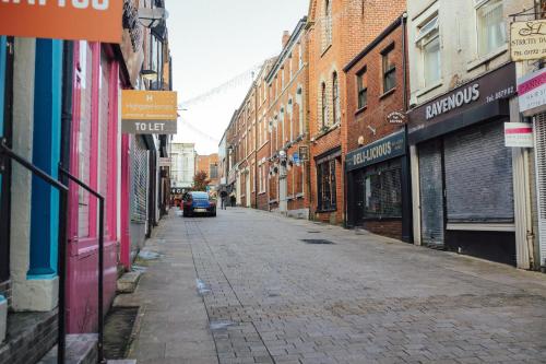 an empty city street with buildings and a car parked on the street at 7 Cannon Street in Preston
