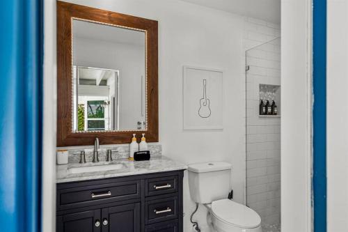 W łazience znajduje się umywalka, lustro i toaleta. w obiekcie Shady Grove Villa w mieście Boynton Beach