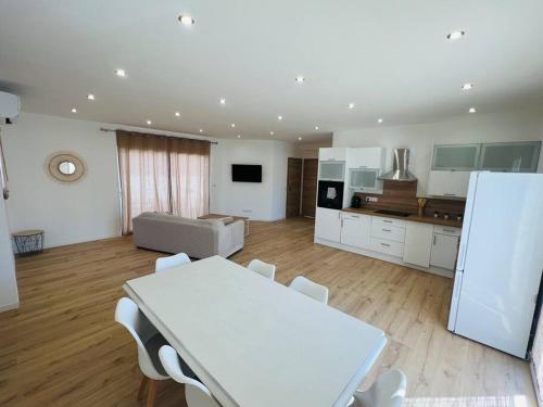 - une cuisine avec une table blanche et des chaises blanches dans l'établissement Belle villa neuve avec jardin et parking, à Calenzana