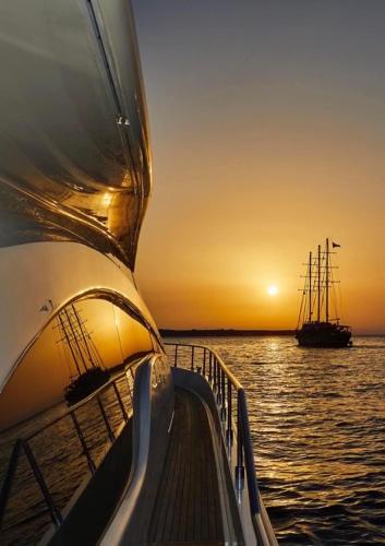 a boat in the water at sunset with a ship at Costos Condos NEW 10B 2 Bedrooms Condo in Nafpaktos