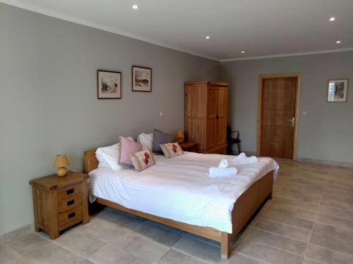 a bedroom with a large bed with white sheets and pink pillows at Villa Rose above Agni with amazing views in Kavalléraina