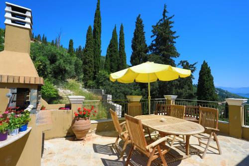 a patio with a table and chairs and an umbrella at Villa Rose above Agni with amazing views in Kavalléraina