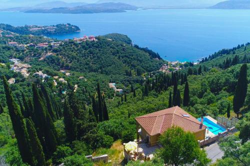 a house on a hill with trees and water at Villa Rose above Agni with amazing views in Kavalléraina