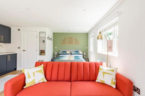 a living room with a red couch and a bed at Charming Chester Studio with private garden & free parking in Chester