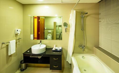 un baño con lavabo y bañera en Diva Hotel, en Manama