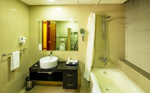 a bathroom with a sink and a bath tub at Diva Hotel in Manama