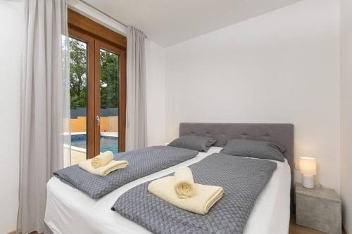 a white bedroom with two beds with towels on them at Villa Dani by IstriaLux in Rovinjsko Selo