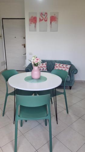 a table with chairs and a vase with flowers on it at La casa verde di Chicchi in Elmas