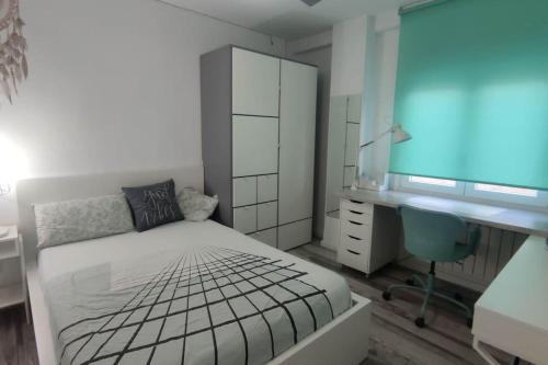 a white bedroom with a bed and a desk and a desk at Apartamento Turquesa in Zaragoza