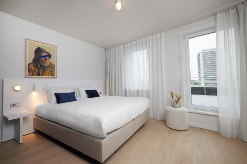 a white bedroom with a large bed and a window at C-Hotels Burlington in Ostend