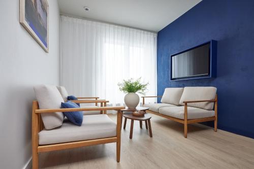 a living room with two chairs and a tv at C-Hotels Burlington in Ostend