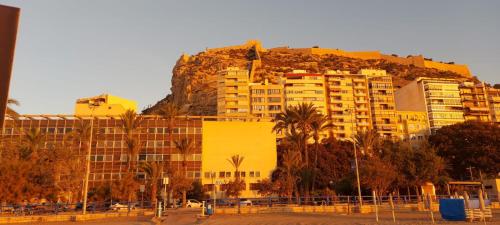 un grande edificio giallo con una montagna dietro di esso di SanFernando14 ad Alicante