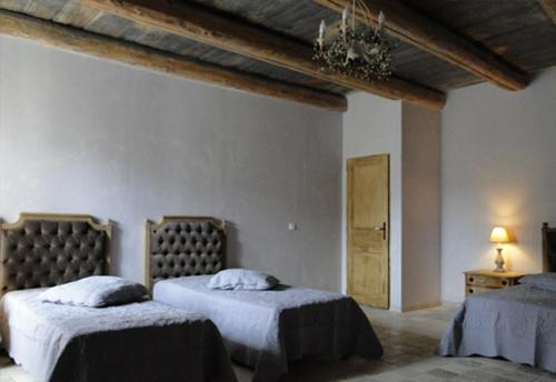 a bedroom with two beds with white sheets and a ceiling at Le Préau in Vallon-Pont-dʼArc