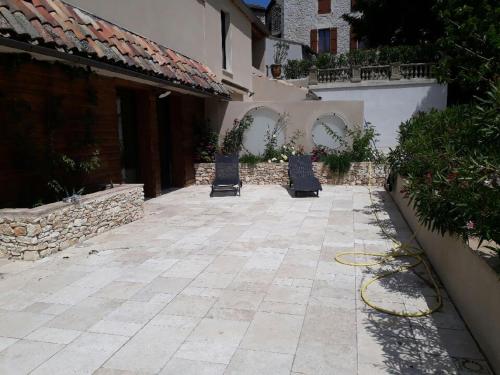 two chairs sitting on a patio next to a building at Le Préau in Vallon-Pont-dʼArc