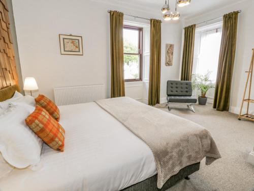 a bedroom with a large white bed and a chair at Brewery House in Newton Stewart