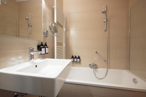 a bathroom with a sink and a shower and a tub at C-Hotels Burlington in Ostend