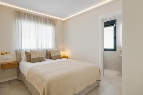 a white bedroom with a large bed and a window at Casa Las Palmeras in Marbella