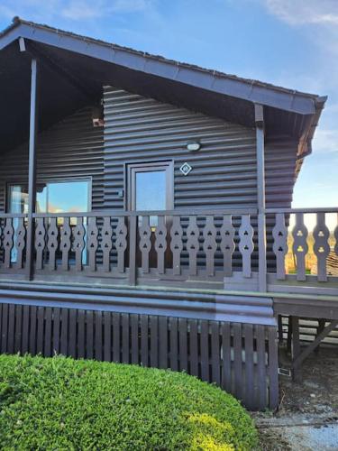 a wooden house with a wooden fence in front of it at Hideaway Lodge in Carnforth