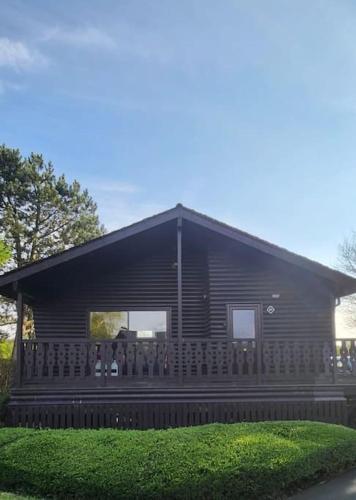 a log cabin with a fence in front of it at Hideaway Lodge in Carnforth
