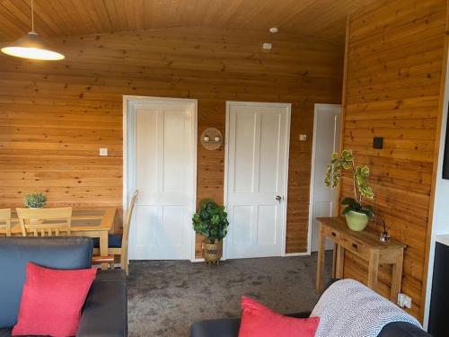 a living room with wooden walls and a table and a couch at Hideaway Lodge in Carnforth