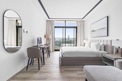 Schlafzimmer mit einem Bett, einem Schreibtisch und einem Spiegel in der Unterkunft A Living Luxury Studio Nicholas Residence JVC in Dubai