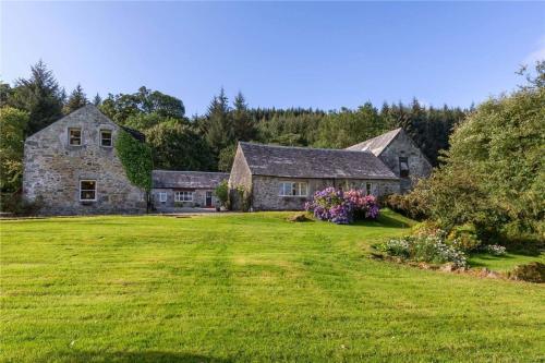 una antigua casa de piedra con un gran patio en Killean Farmhouse Cottages, 