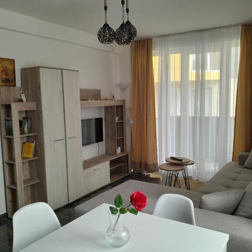 a living room with a couch and a table with a rose on it at Spa Koncept-Apartmani in Veliko Gradište