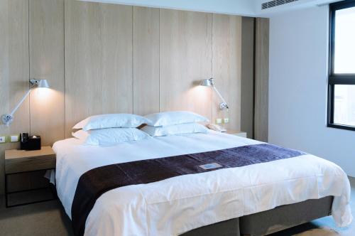 a bedroom with a large bed with white sheets and pillows at Gogo Hotel in Taichung