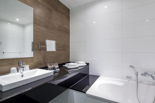 La salle de bains blanche est pourvue d'un lavabo et d'un miroir. dans l'établissement Van der Valk hotel Harderwijk, à Harderwijk