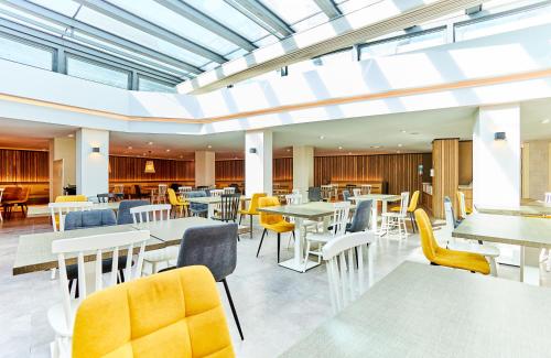 a restaurant with white tables and yellow chairs at Leonardo Royal Hotel Mallorca in Palmanova