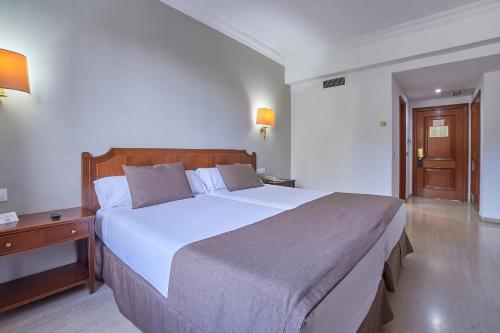 a bedroom with a large white bed with a wooden headboard at Crisol Jardines de Córdoba in Córdoba