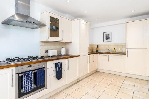 a kitchen with white cabinets and a stove top oven at Fortified 4 Bedroom Holly Lodge in Bristol