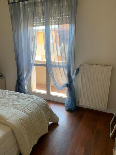 a bedroom with a bed and a window with blue curtains at casa felice in Carrara