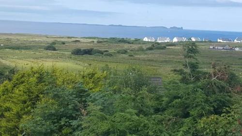 a green field with trees and houses in the distance at Tobar Na Si Apartments in Letterkenny