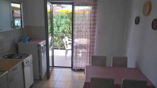 une cuisine avec une table et une porte donnant sur une terrasse. dans l'établissement Apartments Krešo, à Starigrad-Paklenica
