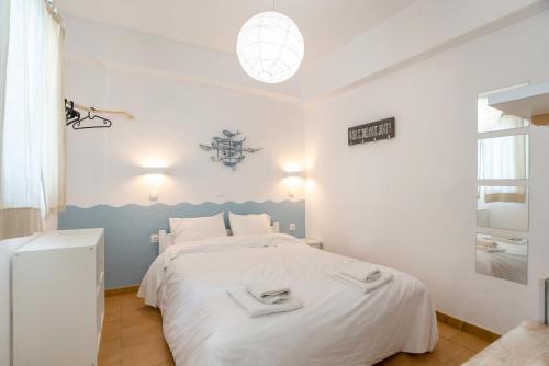 a bedroom with a white bed with a blue headboard at Livadia Seaside Studios 6 in Parikia
