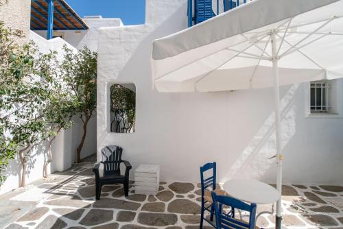 a white building with a table and chairs and an umbrella at Livadia Seaside Studios 6 in Parikia