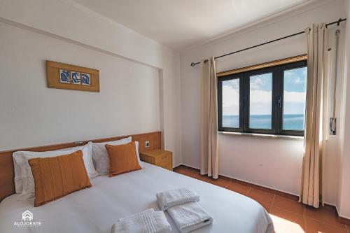 a bedroom with a bed and a large window at Ondas do Pisão Apartment - 2 bedroom and Sea View in Santa Cruz