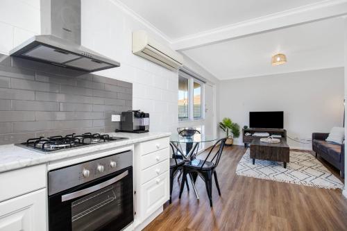 a kitchen with a stove and a living room at Gateway Retreat near Flinders Uni & Hospital in Sturt