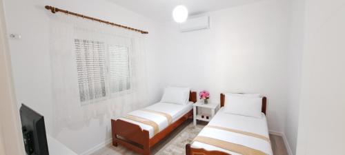 Habitación blanca con 2 camas y TV. en Vila LIKAJ, en Berat