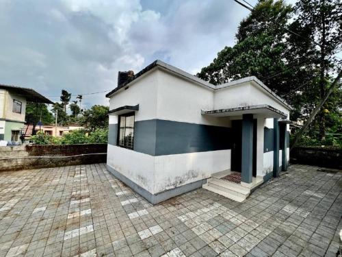 a small white and black house with a brick driveway at Casita Riverside Villas in Vythiri