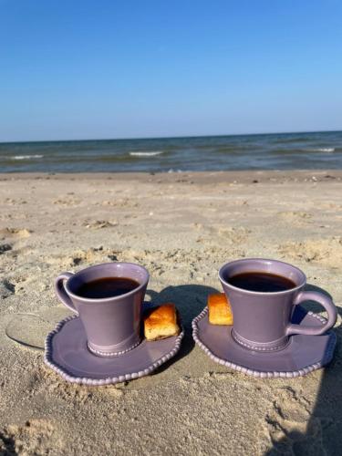 two cups of coffee and bread on the beach at Katrina Summer House in Jūrmalciems