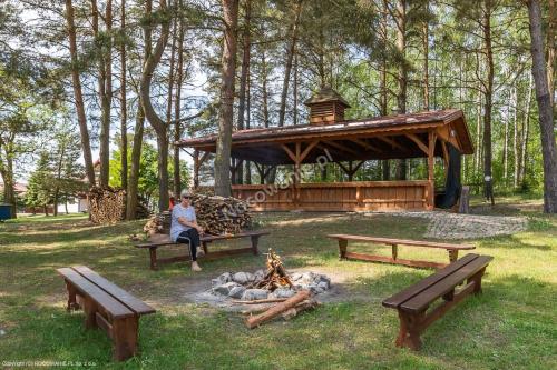 a woman sitting next to a fire in a park at Mimoza Gospodarstwo Agroturystyczne in Bartoszyce
