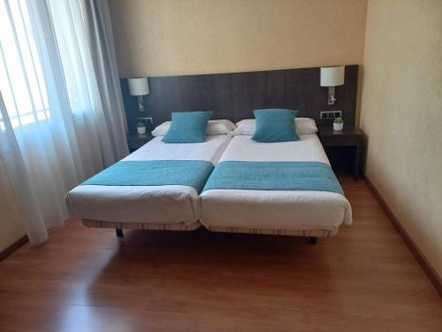 a bedroom with a large bed with blue pillows at Hotel 1948 Manresa in Manresa