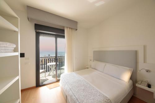 ein weißes Schlafzimmer mit einem Bett und einem Balkon in der Unterkunft Hotel El Salvador Frontemare Piscina Riscaldata in Lido di Jesolo