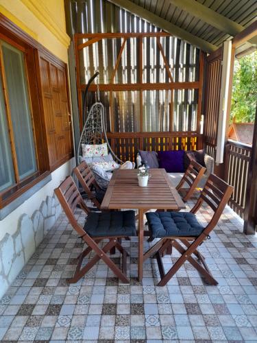 una mesa de madera y sillas en un porche en Nárcisz Vendégház 2, en Mezőkövesd