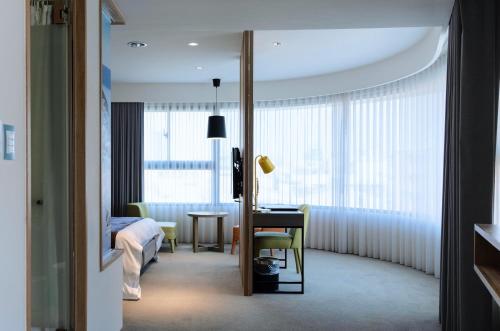 een hotelkamer met een bed, een tafel en een raam bij Gogo Hotel in Taichung