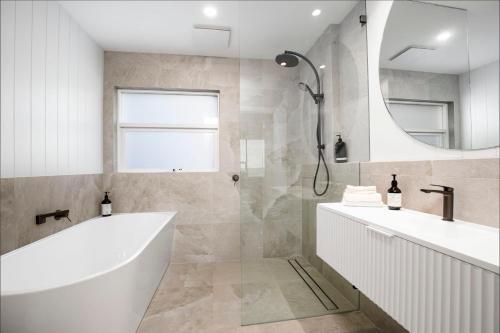La salle de bains est pourvue d'une baignoire, d'un lavabo et d'un miroir. dans l'établissement Luxury Beachfront Retreat on Henley Beach Esplanade, à Henley Beach South