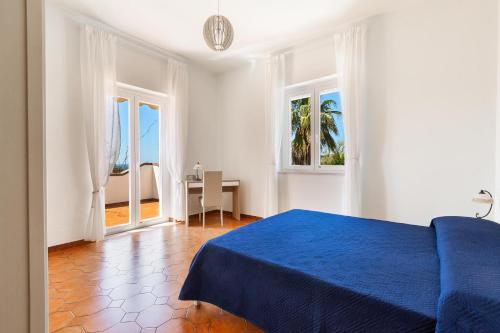 a bedroom with a blue bed and a table and windows at Villa Sunkiss by Perle di Puglia in Pulsano